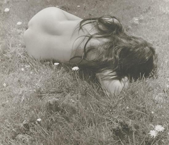 Josef Breitenbach-back view of female nude with long dark hair lying curled on grass, 1961
