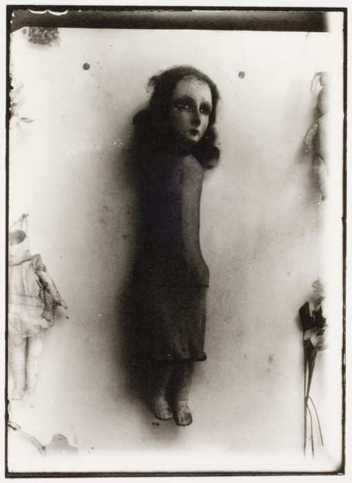 Fred Stein- Armless doll in long dress hanging on wall   , 1935